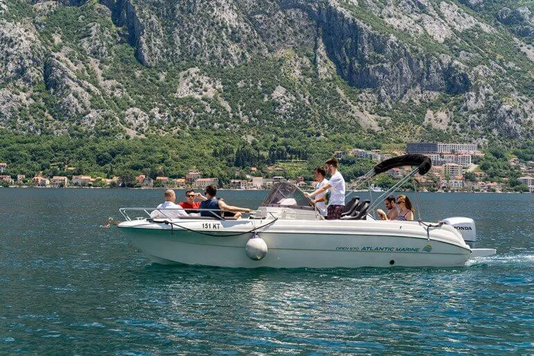 Para odpoczywa na wynajętej łodzi, w tle góry Zatoki Kotorskiej