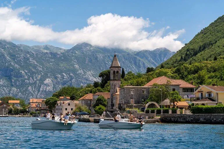 Łódź motorowa mija nadmorską wioskę Prčanj w zatoce