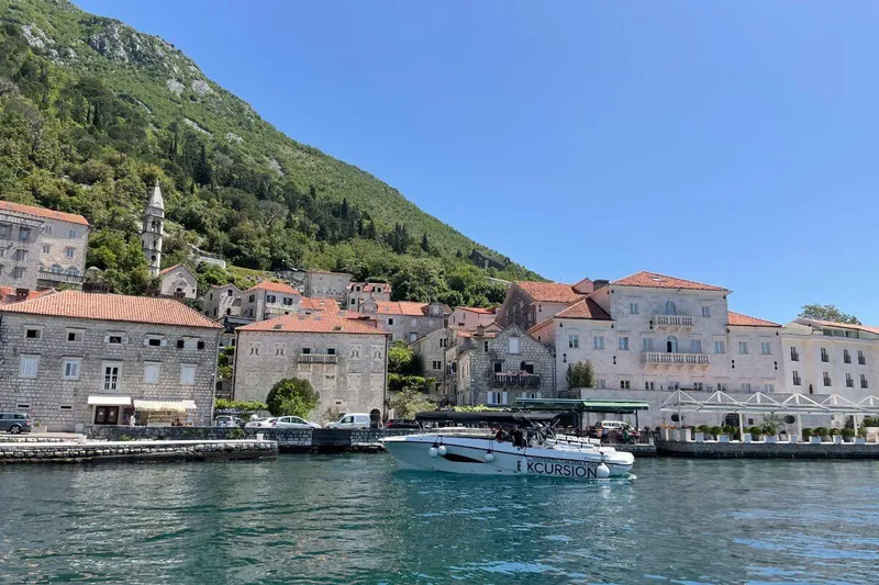 Goście pływają w osłoniętej zatoczce z widokiem na góry w Boce Kotorskiej Goście pływają w osłoniętej zatoczce z widokiem na góry w Boce Kotorskiej