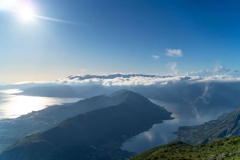 Barca veloce in partenza dal porto di Kotor con le mura della città vecchia alle spalle Barca veloce in partenza dal porto di Kotor con le mura della città vecchia alle spalle
